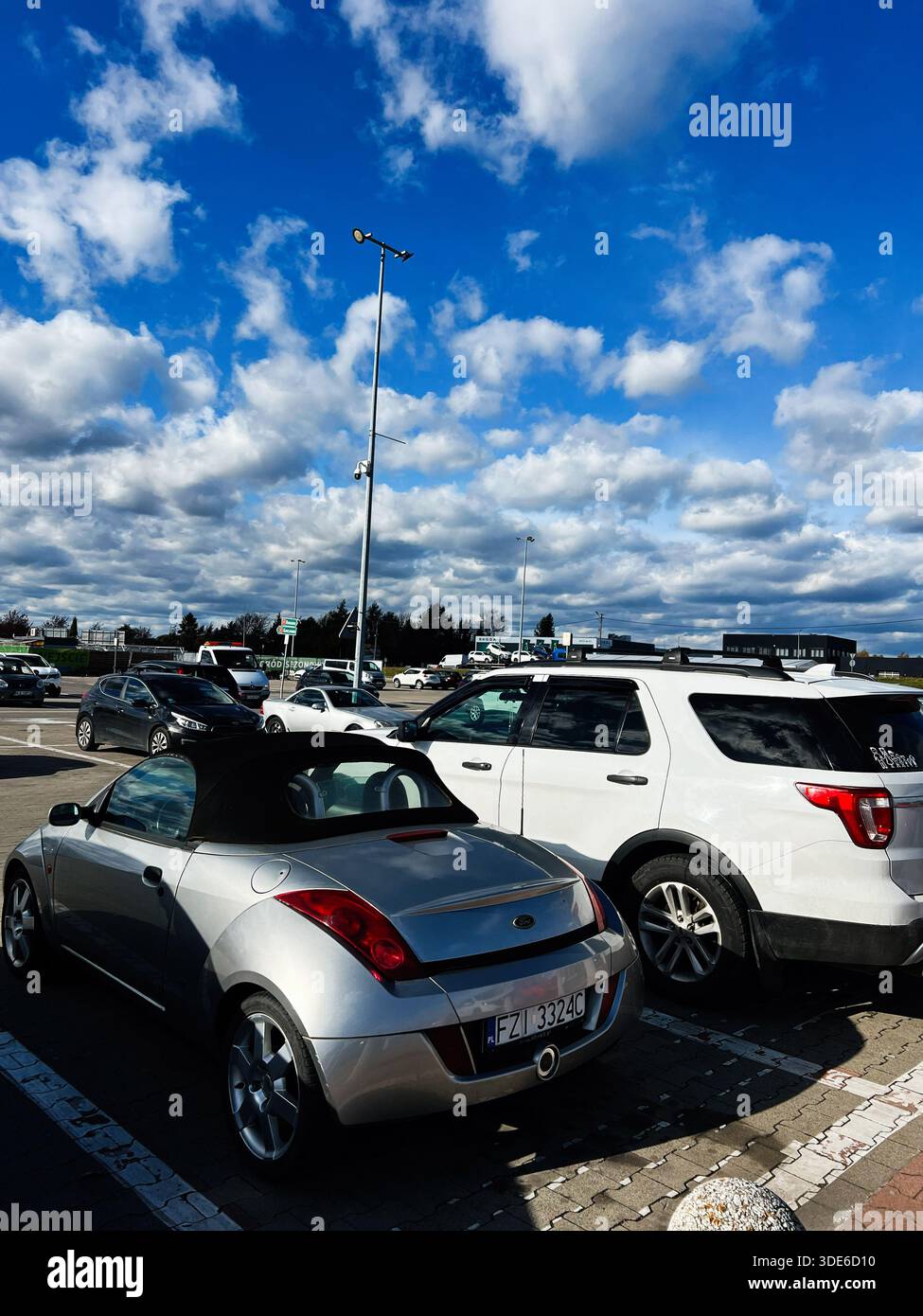 Rzeszow, Polonia - 29 novembre 2025: Ford StreetKa convertibile argento accanto a un SUV Ford Explorer bianco in un luminoso parcheggio all'aperto con un drammatico Foto Stock