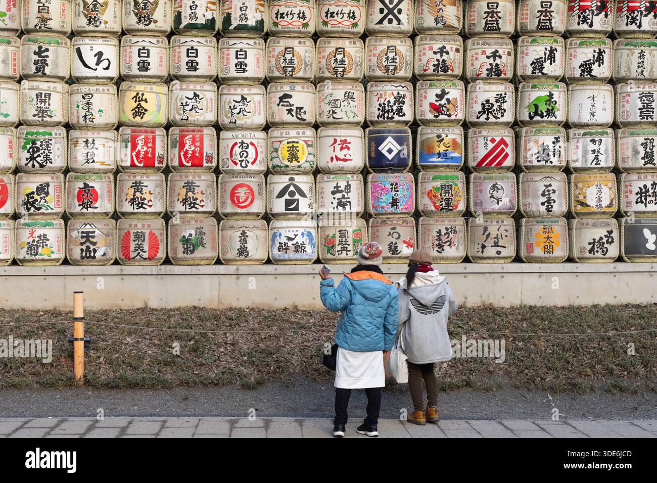 Due persone ammirano le botti di sake al santuario Meiji Jingu, in Giappone. Foto Stock