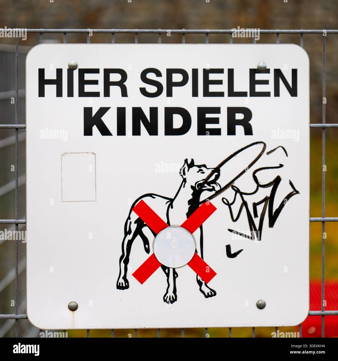 Insegna tedesca Hier Spielen Kinder su una recinzione con un pittogramma e graffiti senza cani Foto Stock