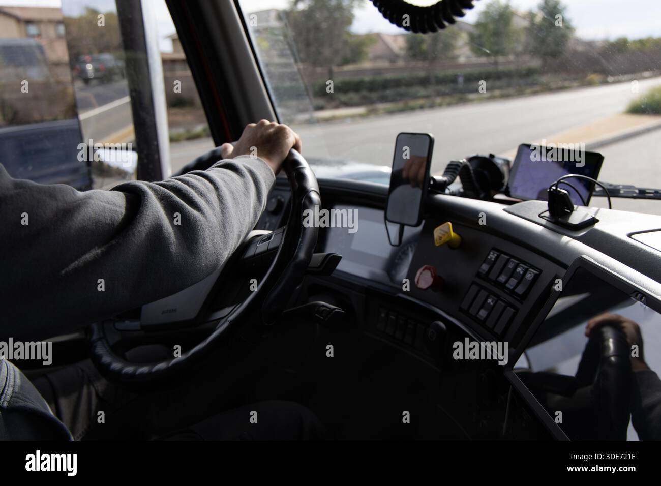 Una persona è al volante di un veicolo di grandi dimensioni su una strada. Il conducente utilizza attrezzature e attrezzi all'interno dell'abitacolo, concentrandosi sul percorso che precede. Foto Stock