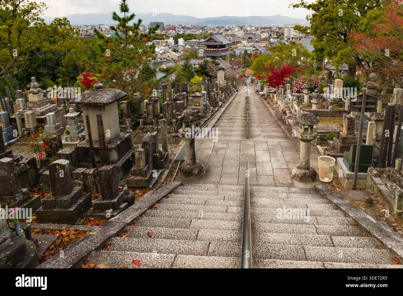 Una lunga scalinata in pietra sale attraverso il cimitero del tempio Konkai Komyo-ji a Kyoto, in Giappone. Il percorso è rivestito da lapidi e conduttori intemprati Foto Stock
