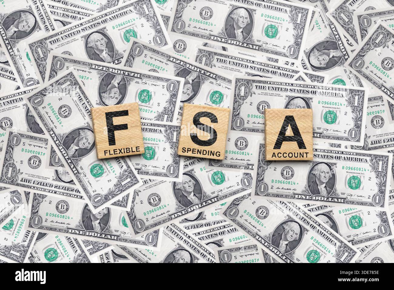 I cubi di legno descrivono FSA con le parole Flexible, spending e account. Le piastrelle sono circondate da un mucchio di banconote in dollari. Concetto di a. Foto Stock