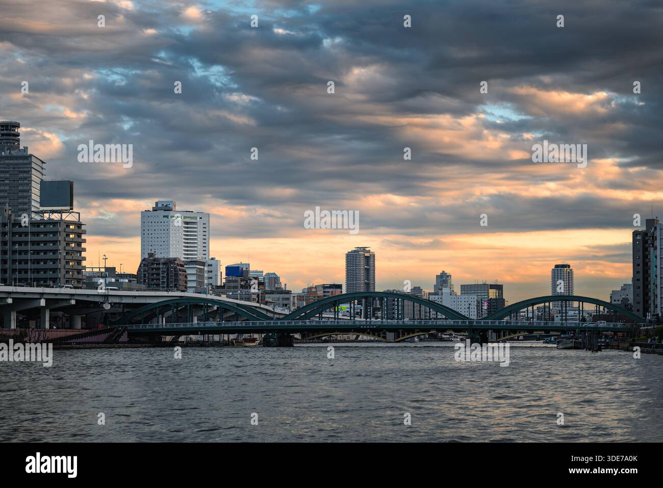 Il tramonto dorato illumina il fiume Sumida di Tokyo, il suo ponte e gli edifici. Foto Stock