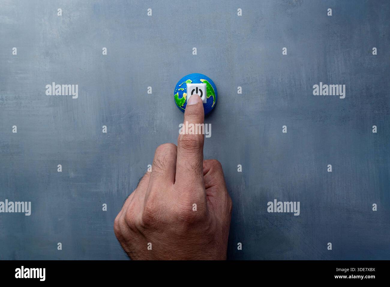 Un dito che preme un pulsante di accensione su un globo in miniatura. Concetto di ora terrestre, risparmio energetico, risparmio energetico. Foto Stock