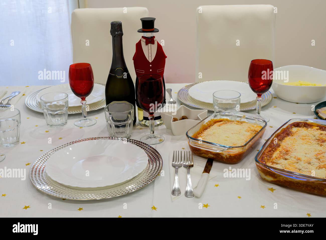Un tavolo con un berretto a forma di cappello e una bottiglia di champagne. Il tavolo è pronto per una cena elegante Foto Stock
