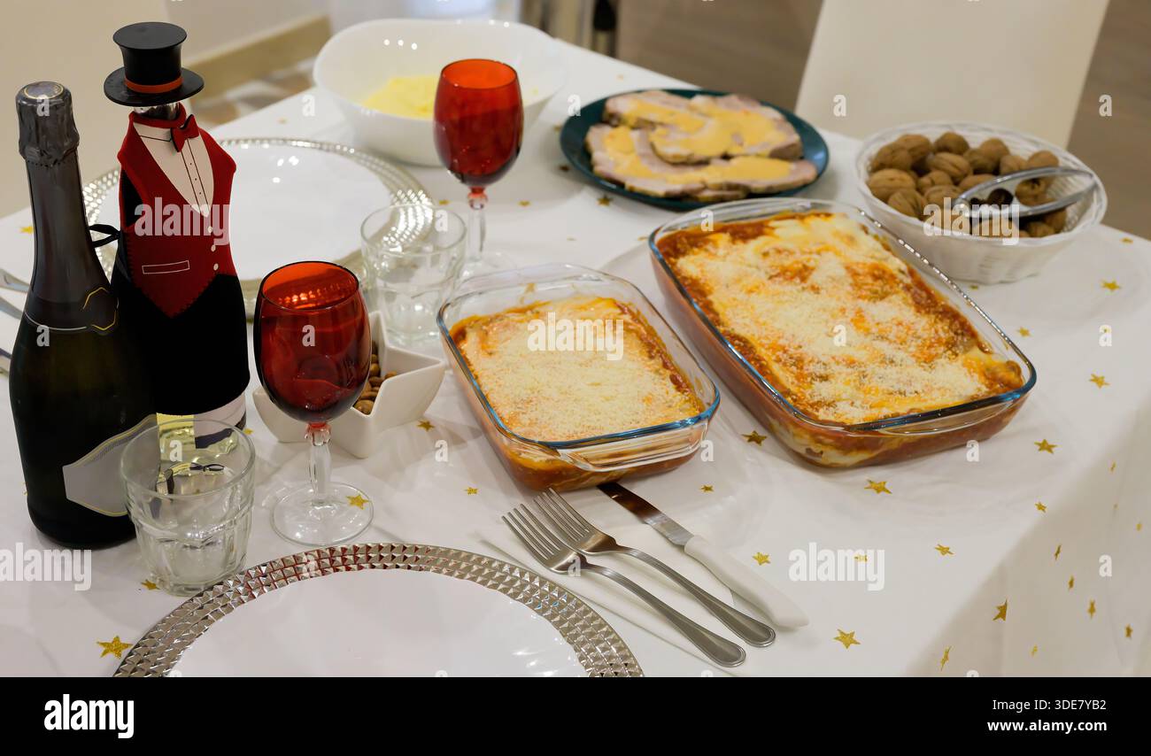 Un tavolo con un berretto a forma di cappello e una bottiglia di champagne. Il tavolo è pronto per una cena elegante Foto Stock
