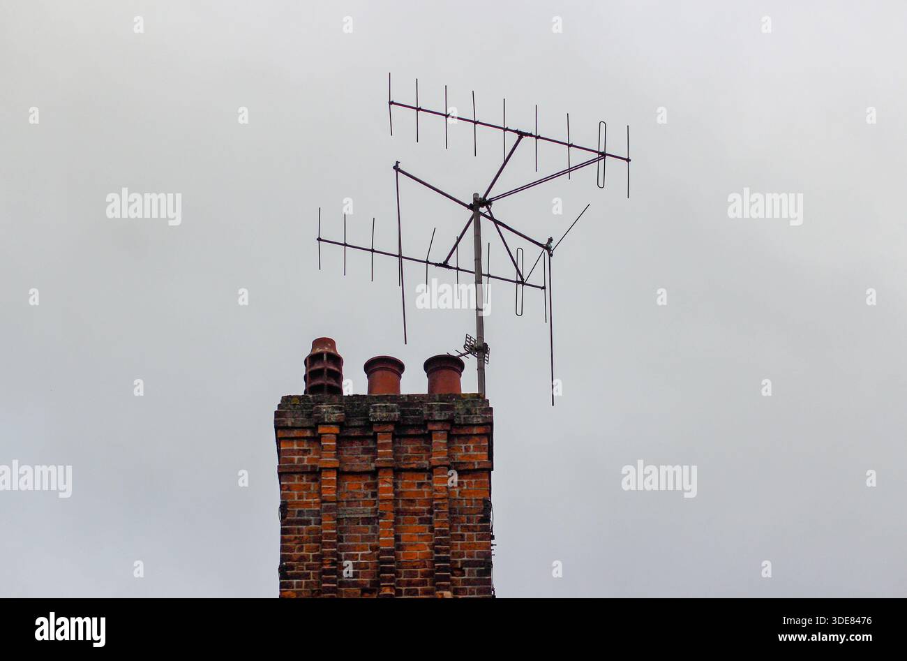 Camini di argilla in cima alla pila di camini di mattoni rossi di una casa residenziale inglese con antenna TV collegata in cima. Oxford, Regno Unito. Foto Stock
