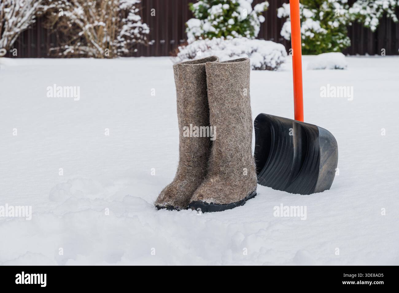 Tazza in acciaio inox con bevanda calda sulla neve accanto al cestello in vimini con coni di pino e thermos. Momenti invernali all'aperto nella natura innevata. Foto Stock