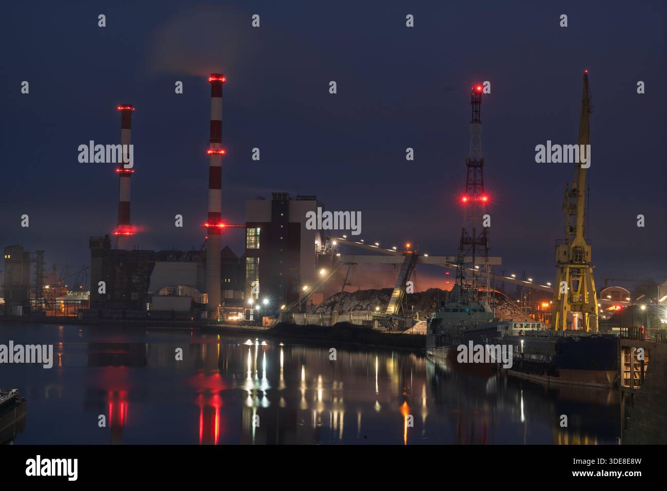 La centrale combinata di calore ed energia elettrica di notte, riflessa nell'acqua Foto Stock