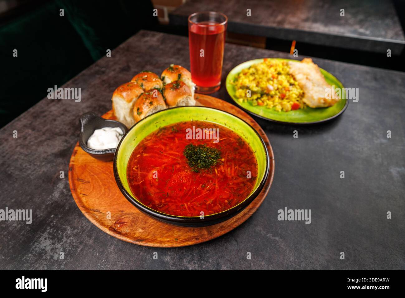 Un tavolo presenta ciotole di abbondante zuppa, panini ripieni, riso fritto e una bevanda rinfrescante. I colori vivaci del cibo creano un'atmosfera invitante Foto Stock