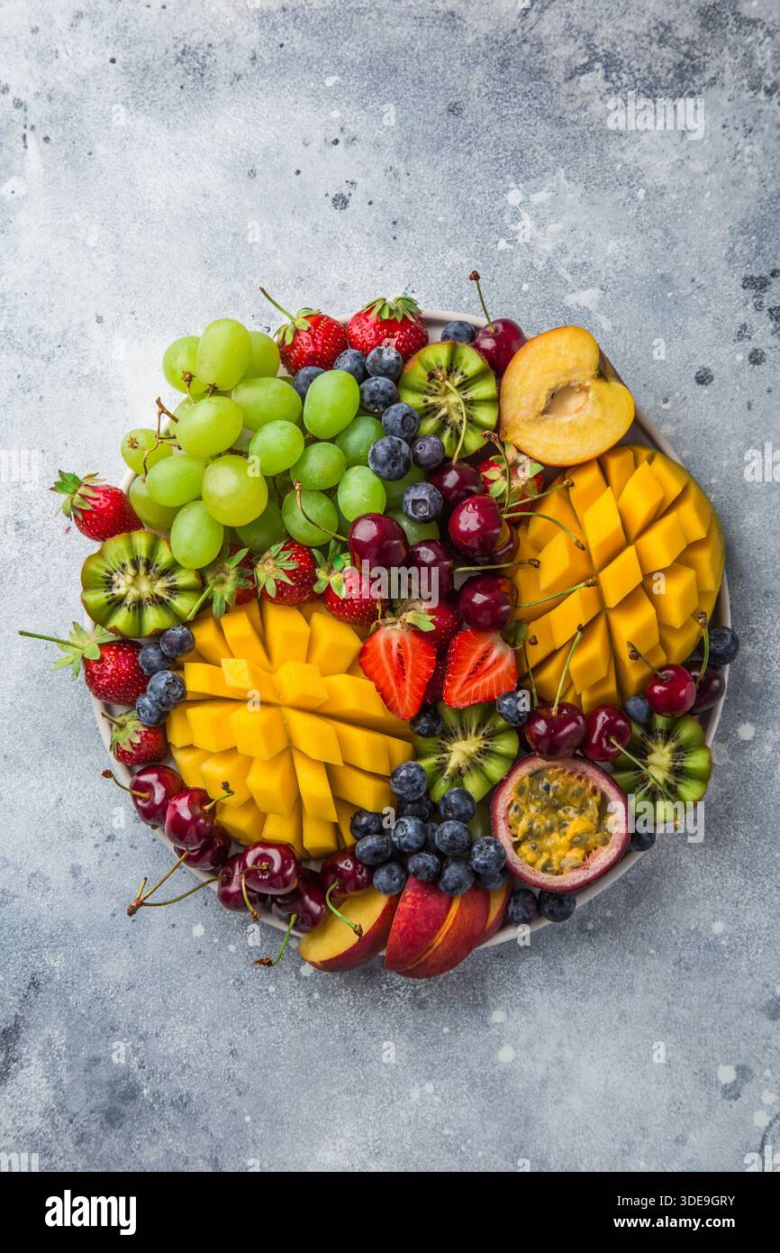 vassoio di frutta e frutti di bosco deliziosi. Mango, kiwi, fragola, uva, ciliegia, mirtillo, pesca e frutto della passione, vista dall'alto Foto Stock