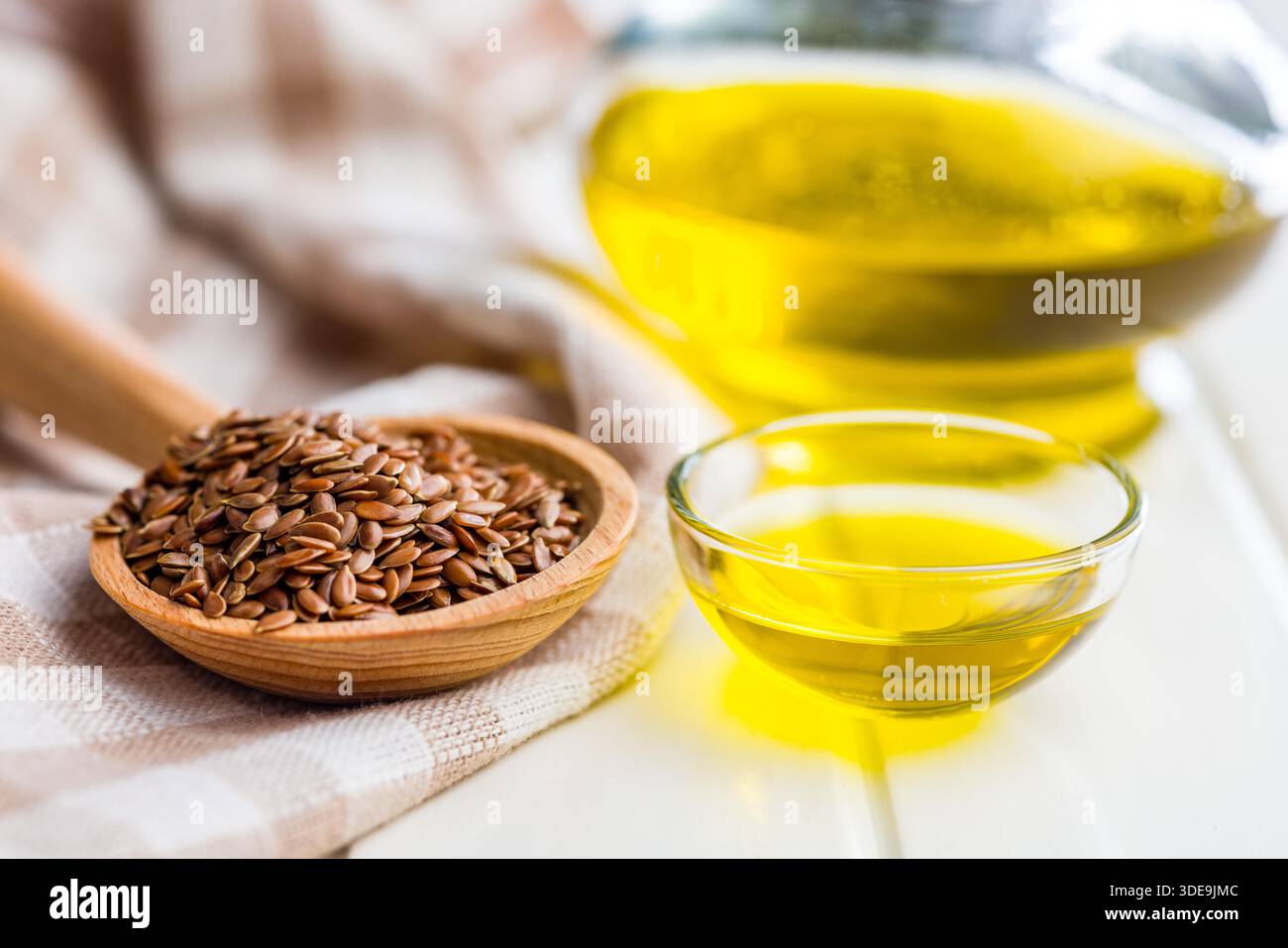 Semi di lino o semi di lino e olio. Sano seme di lino su un cucchiaio di legno su un tavolo bianco. Foto Stock
