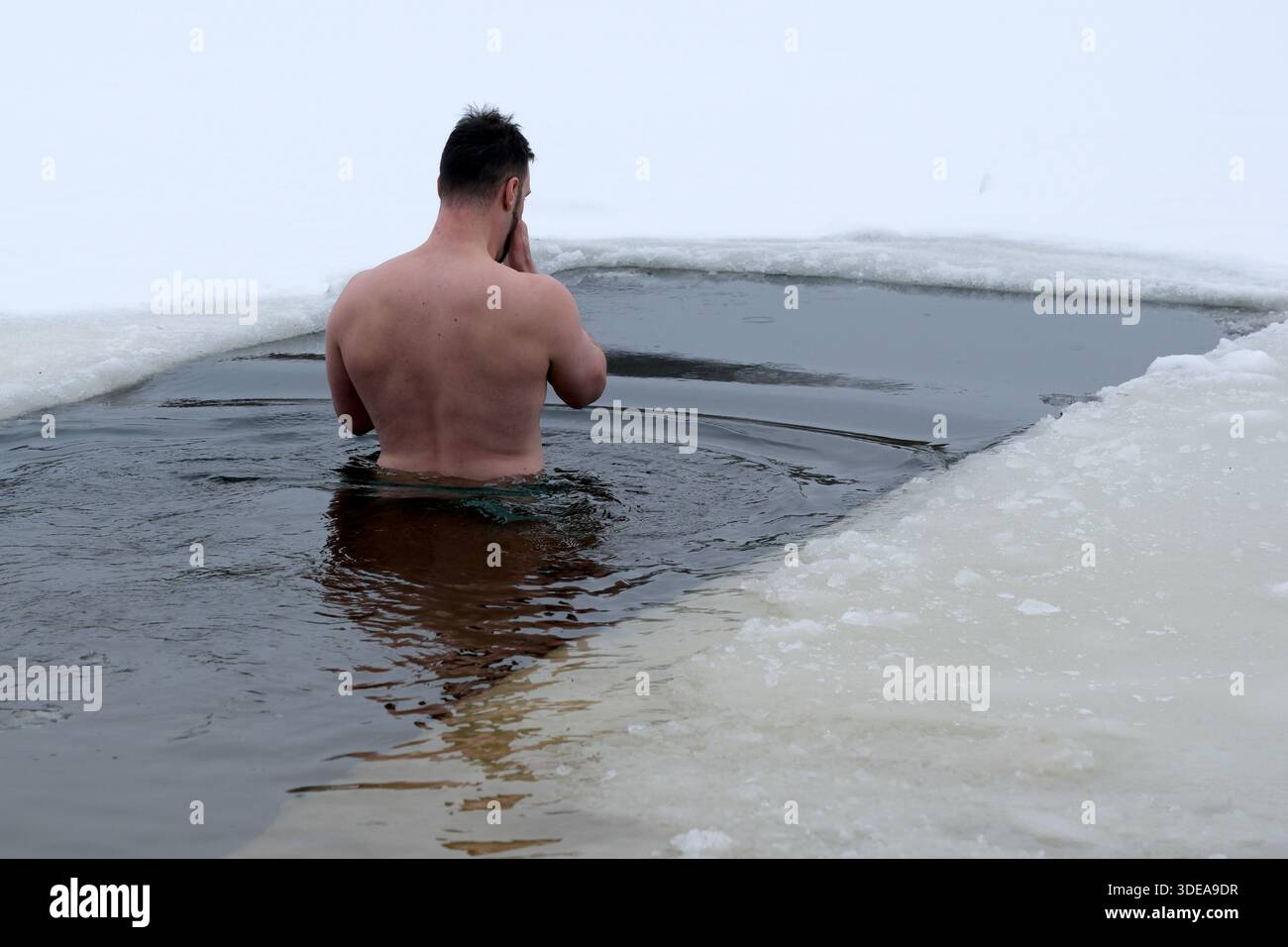Un uomo sta in piedi in acque fredde circondate dal ghiaccio in una giornata invernale, abbracciando il freddo. Kiev, Ucraina, 6 gennaio 2026. Una vasca di ghiaccio sull'Epifania. Foto Stock