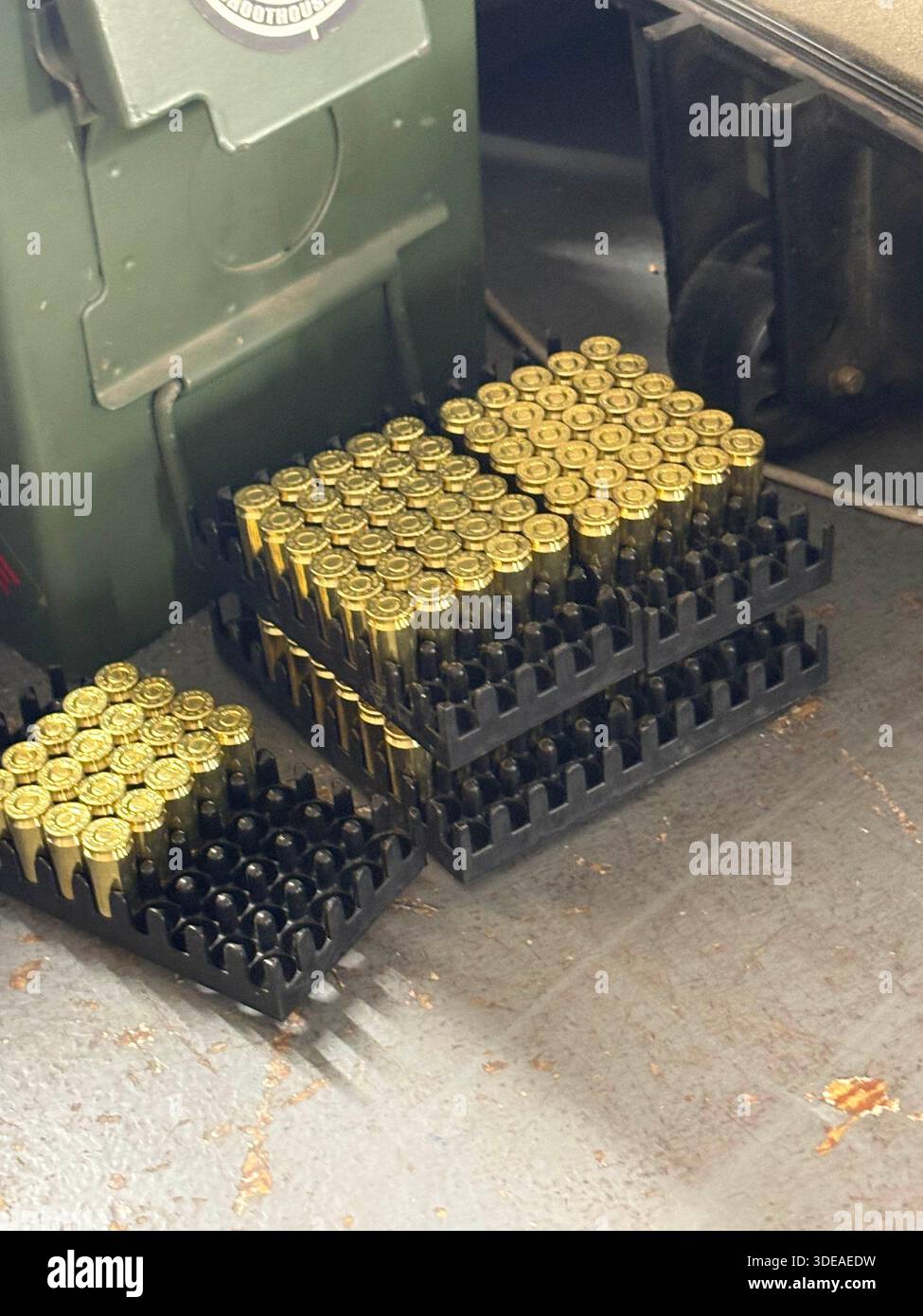 Vassoi organizzati di cartucce a pistola sul pavimento accanto al contenitore verde e al carrello con ruote - Immagine stock catturata con smartphone