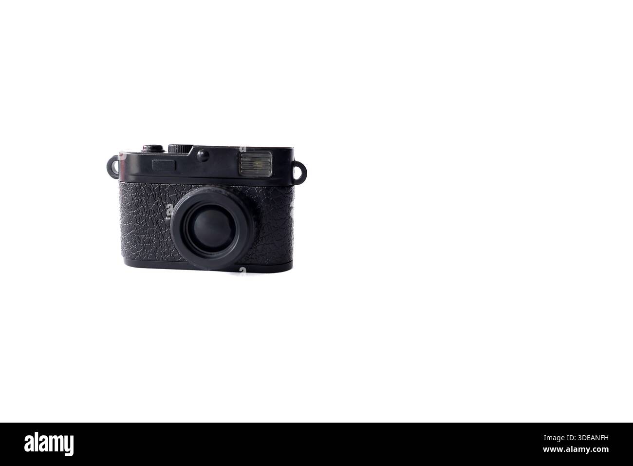 Piccolo giocattolo nero per fotocamera retrò isolato su una superficie bianca semplice con spazio di copia. Concetto di fotografia minimalista. Foto Stock