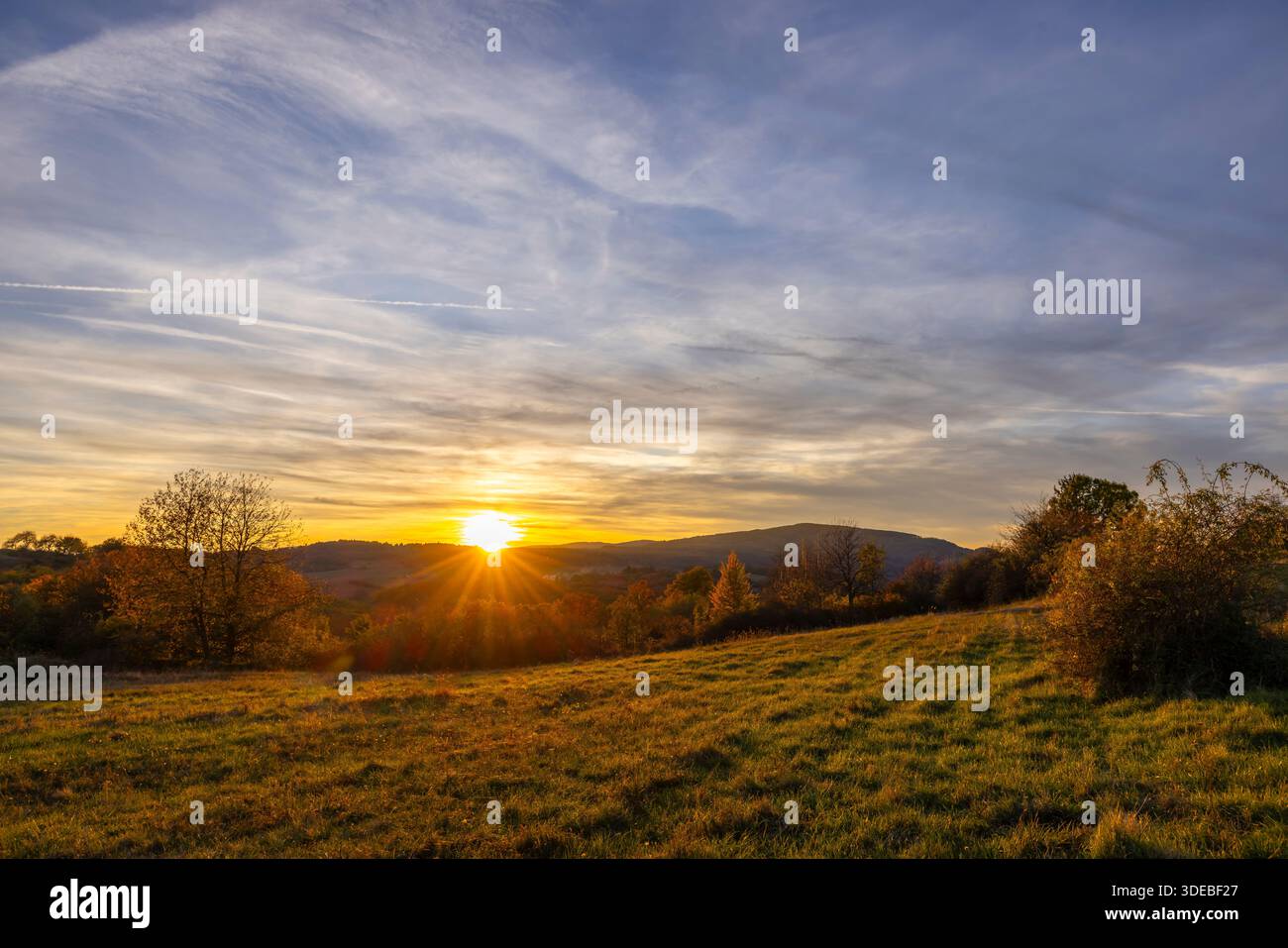 Il sole tramonta in arancione e rosso su un campo rurale autunnale in Slovacchia Foto Stock