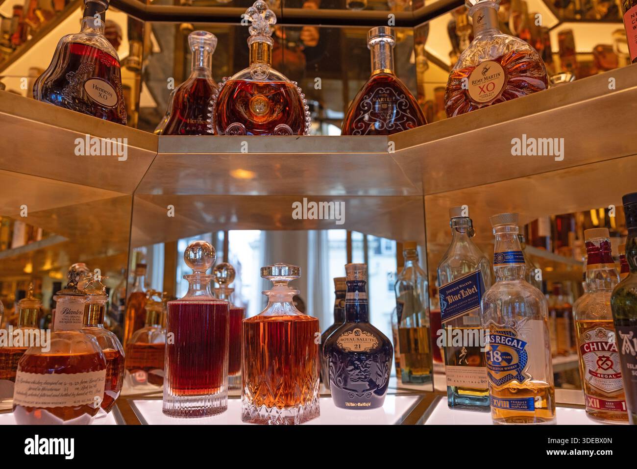 Una collezione curata di biberon cognac artigianali di prima qualità e per piccoli lotti, elegantemente esposti sul ripiano del bar in un ambiente caldo e illuminato. Foto Stock