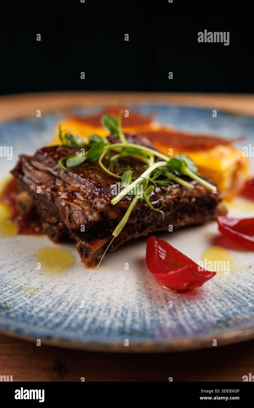 Un ricco piatto di carne di manzo con guarnigioni e contorni colorati, evidenziando la miscela di sapori in un'esperienza culinaria multiculturale. Foto Stock