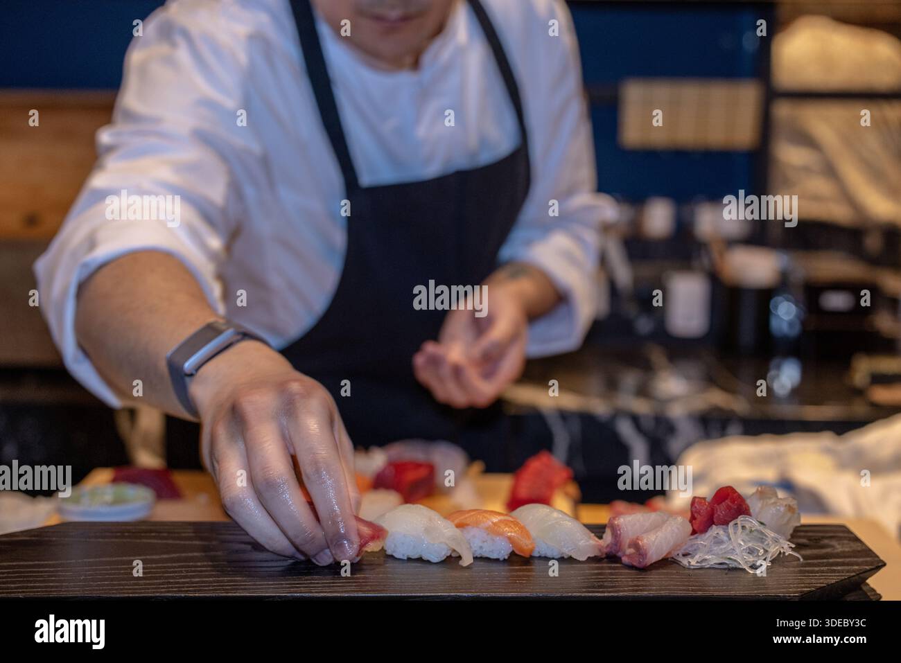 Lo chef sushi prepara meticolosamente sashimi freschi al sushi bar in un esclusivo ristorante giapponese. Foto Stock