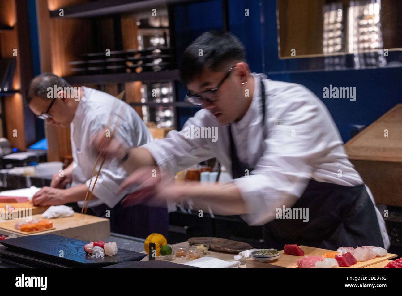Chef di sushi che preparano sashimi freschi al sushi bar in un esclusivo ristorante giapponese. Foto Stock