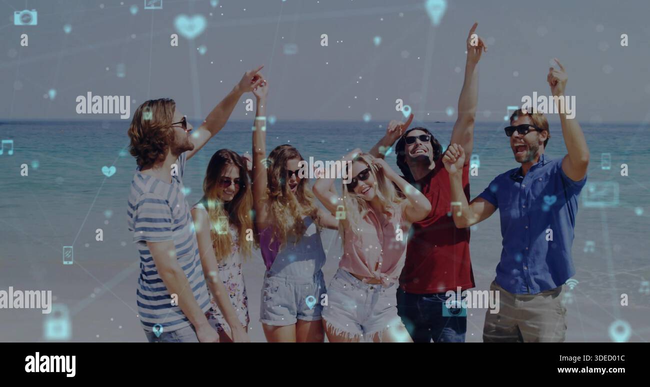 Puntando e sollevando, sei amici in piedi in estate indossano e sfumature sulla spiaggia sabbiosa, le icone si sovrappongono Foto Stock