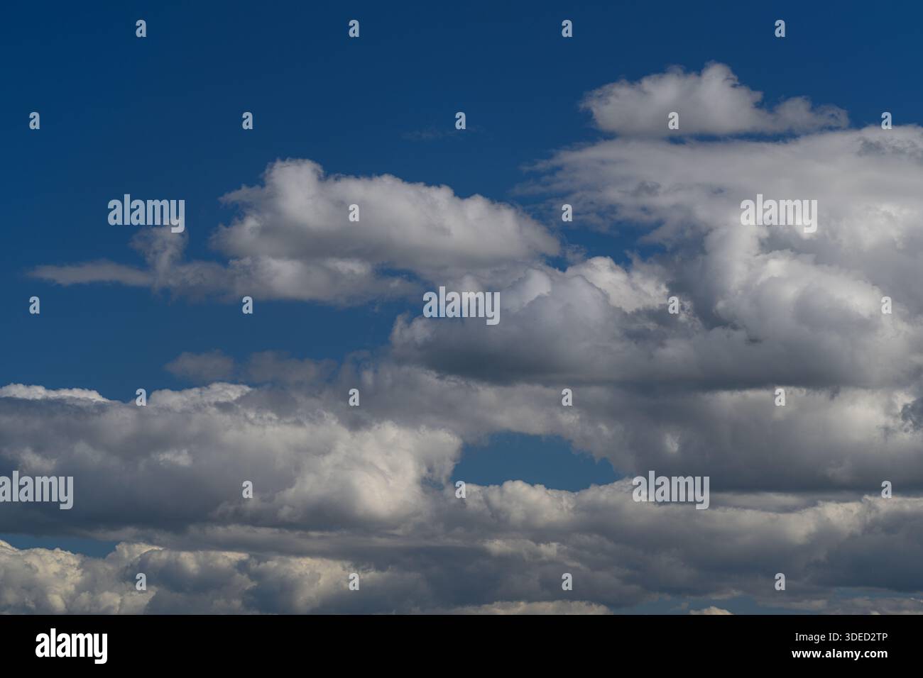 La vista mozzafiato mostra soffici nuvole bianche splendidamente sparse su un vasto cielo blu luminoso Foto Stock