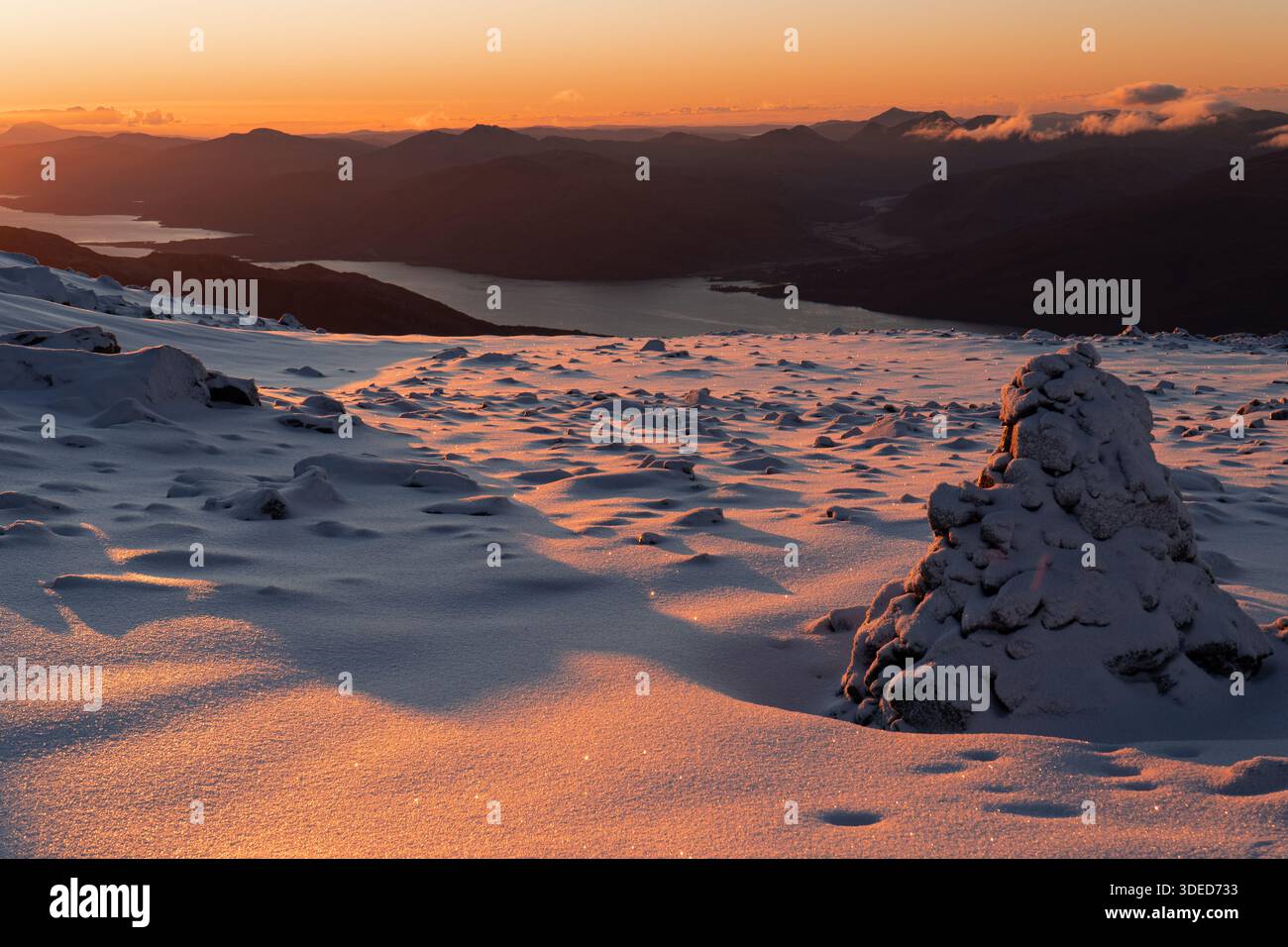 Paesaggio delle montagne innevate all'alba con luce dorata Foto Stock