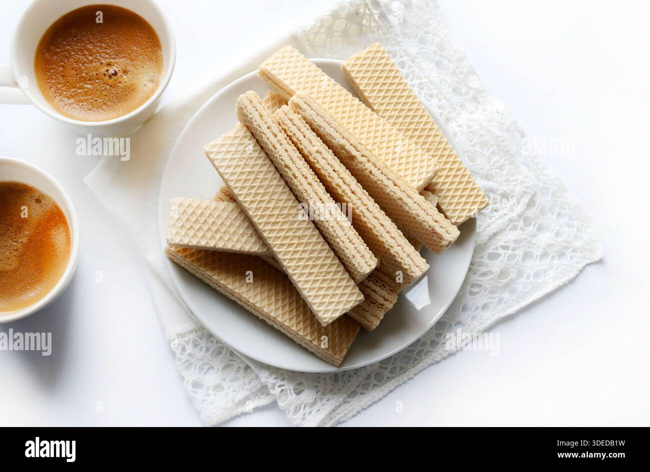 Piastra per wafer e due tazze di caffè isolate su una superficie bianca. Vista dall'alto. Foto Stock
