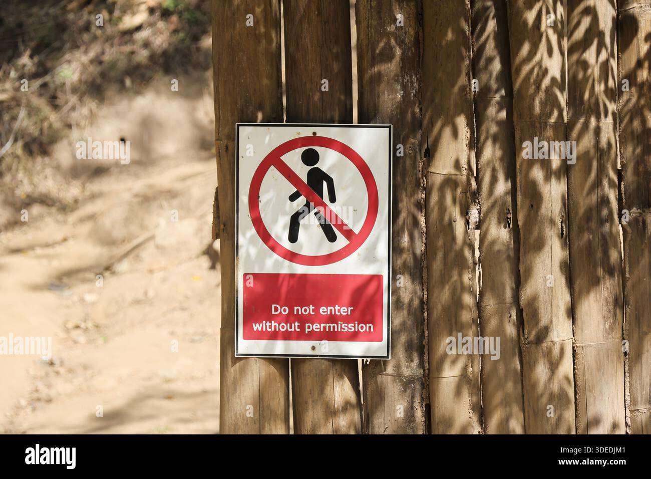 Un cartello di avvertimento rosso e bianco sulla recinzione di legno crea una sensazione di prudenza riguardo alla violazione della zona privata senza permesso Foto Stock