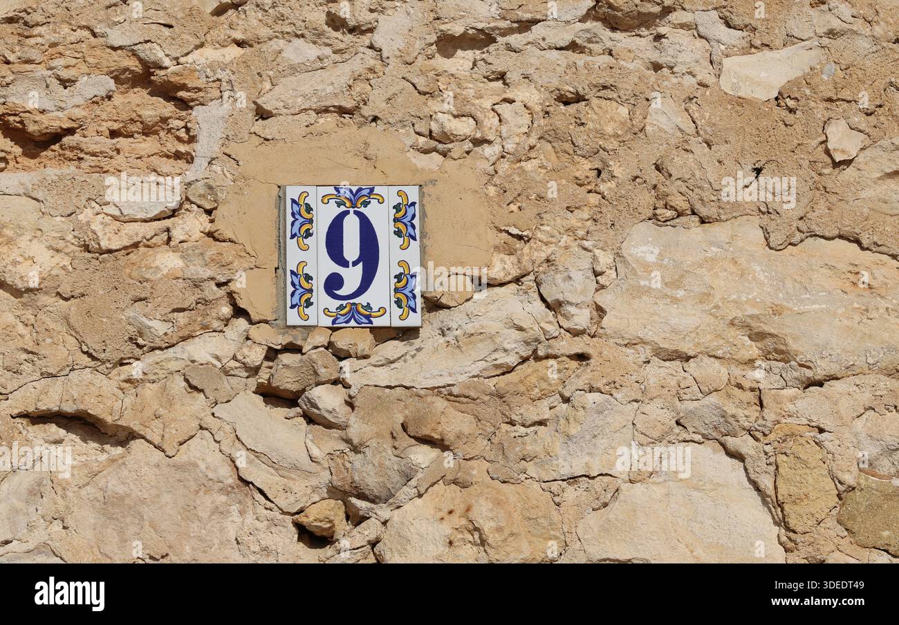 La facciata della casa e' costruita con pietra naturale con il numero civico 9 Foto Stock