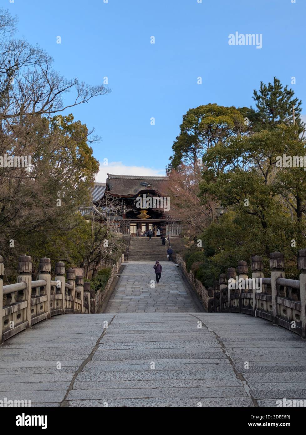 Kyoto, Giappone - febbraio 2025: Ponte di pietra che conduce al tradizionale cancello d'ingresso in legno del complesso del tempio buddista Otani Hombyo a Higashiyama. - Immagine stock catturata con smartphone