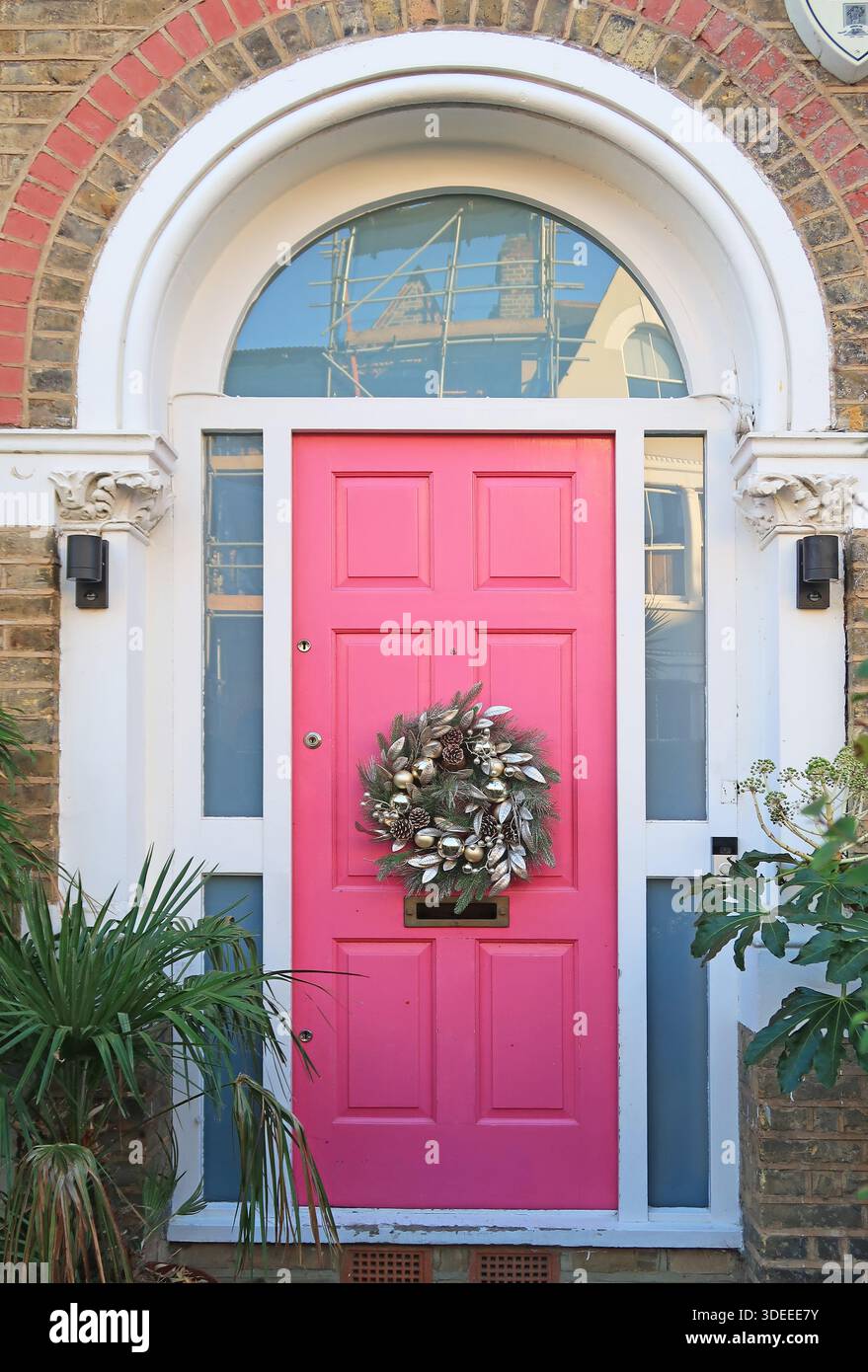 Corona di Natale su una porta d'ingresso rosa brillante di una casa vittoriana nel sud di Londra, Regno Unito. Foto Stock