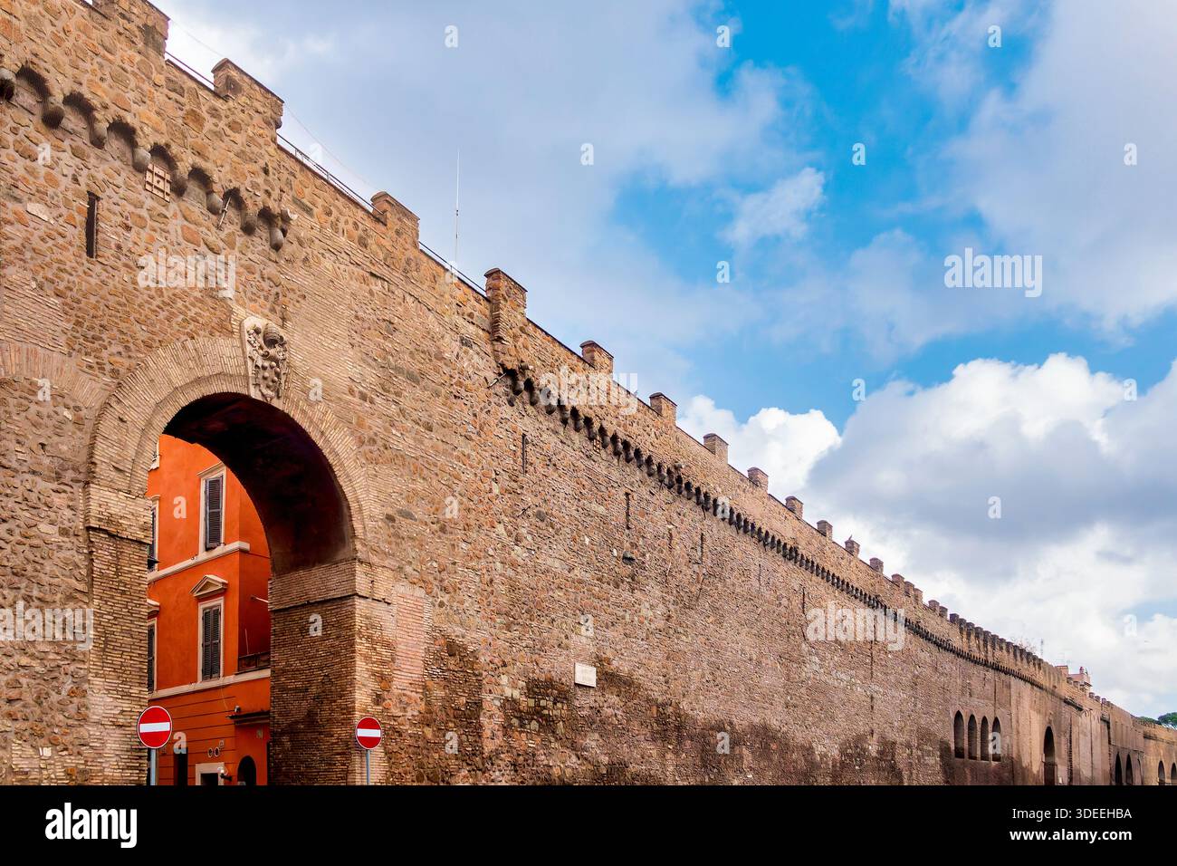 Vista dal basso delle mura del Passetto di Borgo con arco in pietra e edificio rosso a Roma, Italia. Foto Stock