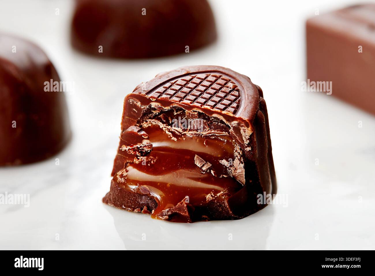 Primo piano di una mezza pralina al cioccolato al latte con ripieno di caramello su un tavolo Foto Stock