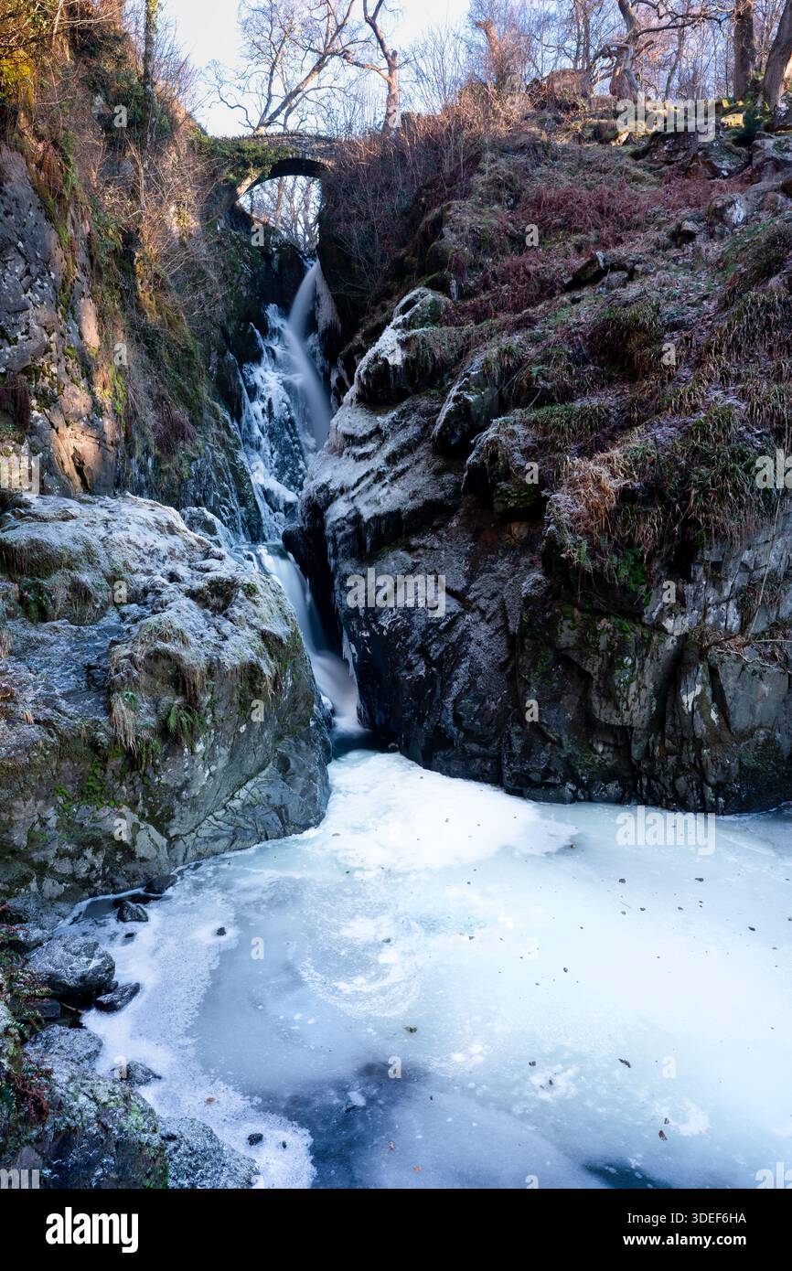 Cascata Aira Force vicino a Ullswater, Lake District, Cumbria, Inghilterra. Rocce ricoperte di ghiaccio e un Aira Beck parzialmente congelato in una giornata invernale molto fredda Foto Stock