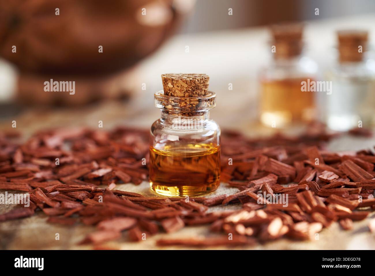 Pezzi di legno di sandalo rosso con una bottiglia in vetro di olio essenziale aromaterapico Foto Stock