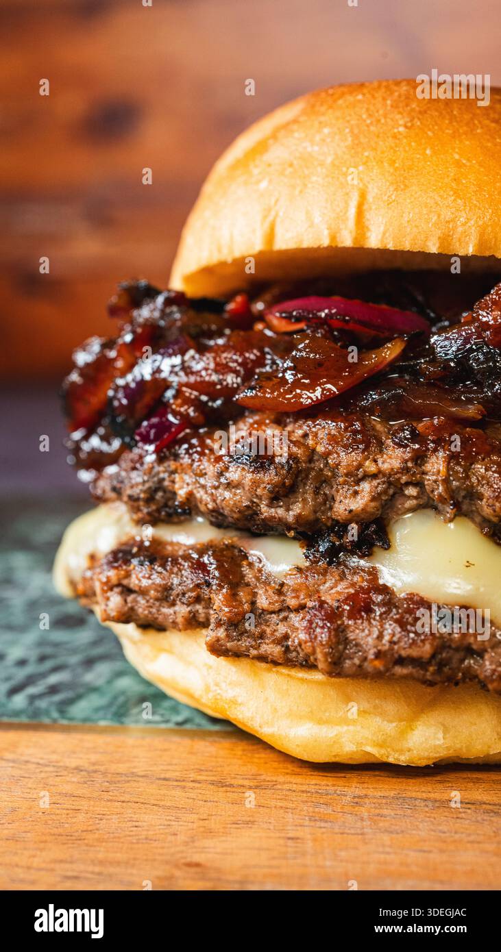 Delizioso cheeseburger con marmellata di pancetta, chutney di cipolle rosse e formaggio fuso. Presentato in modo splendido, sapore dolce-salato, perfetto per gou Foto Stock