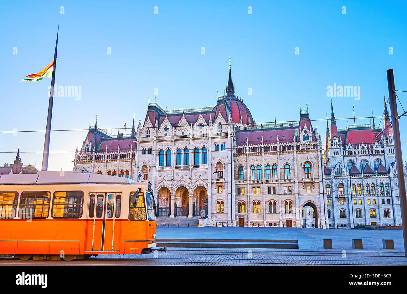 Il vecchio tram giallo corre contro la costruzione del Parlamento in Piazza Lajos Kossuth, Pest, Budapest, Ungheria Foto Stock