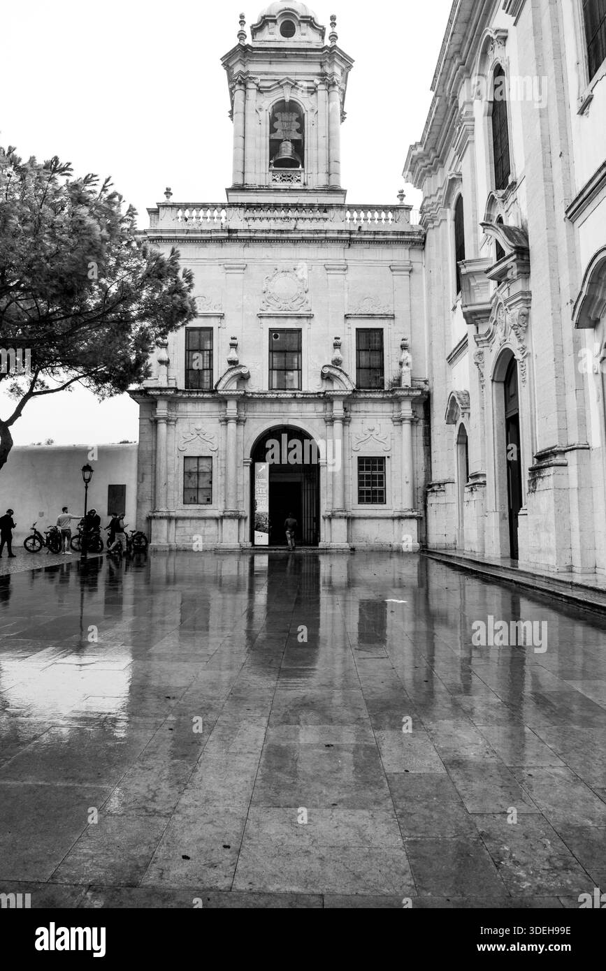 Il convento di Graca è uno dei più antichi di Lisbona. elegante architettura in pietra, ingressi ad arco e un campanile. La pavimentazione in pietra bagnata si riflette Foto Stock