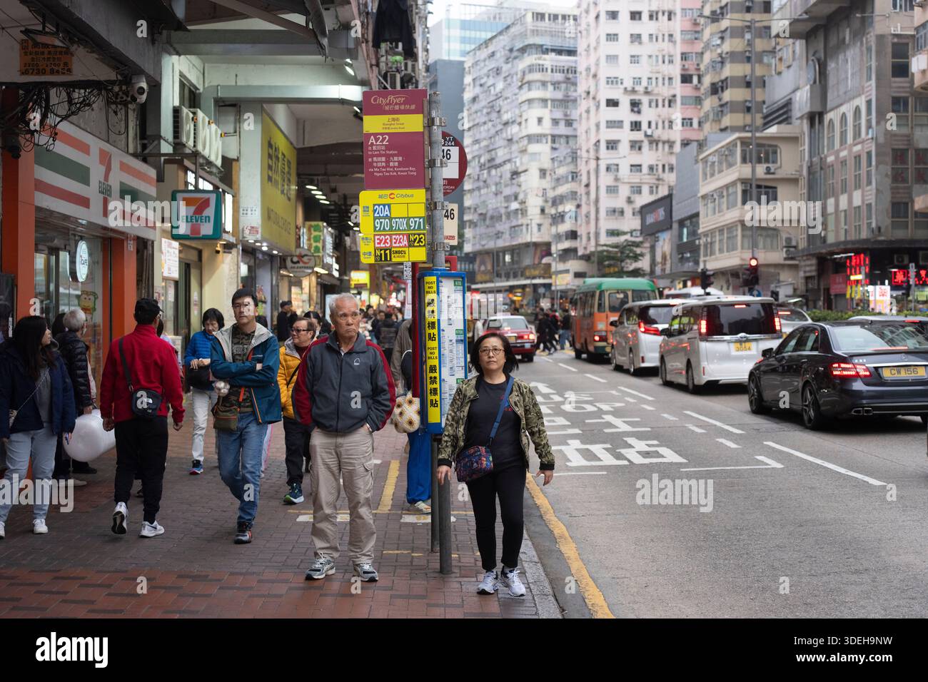 La gente passa davanti a un 7-Eleven, Hong Kong, in attesa di autobus. Foto Stock