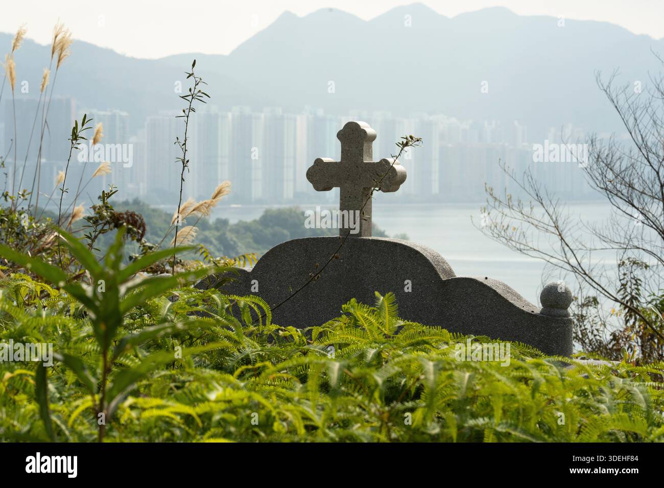 Una lapide a croce si affaccia sul SAM MUN TSAI di Hong Kong, un ricordo del passato in mezzo allo sviluppo urbano. Foto Stock