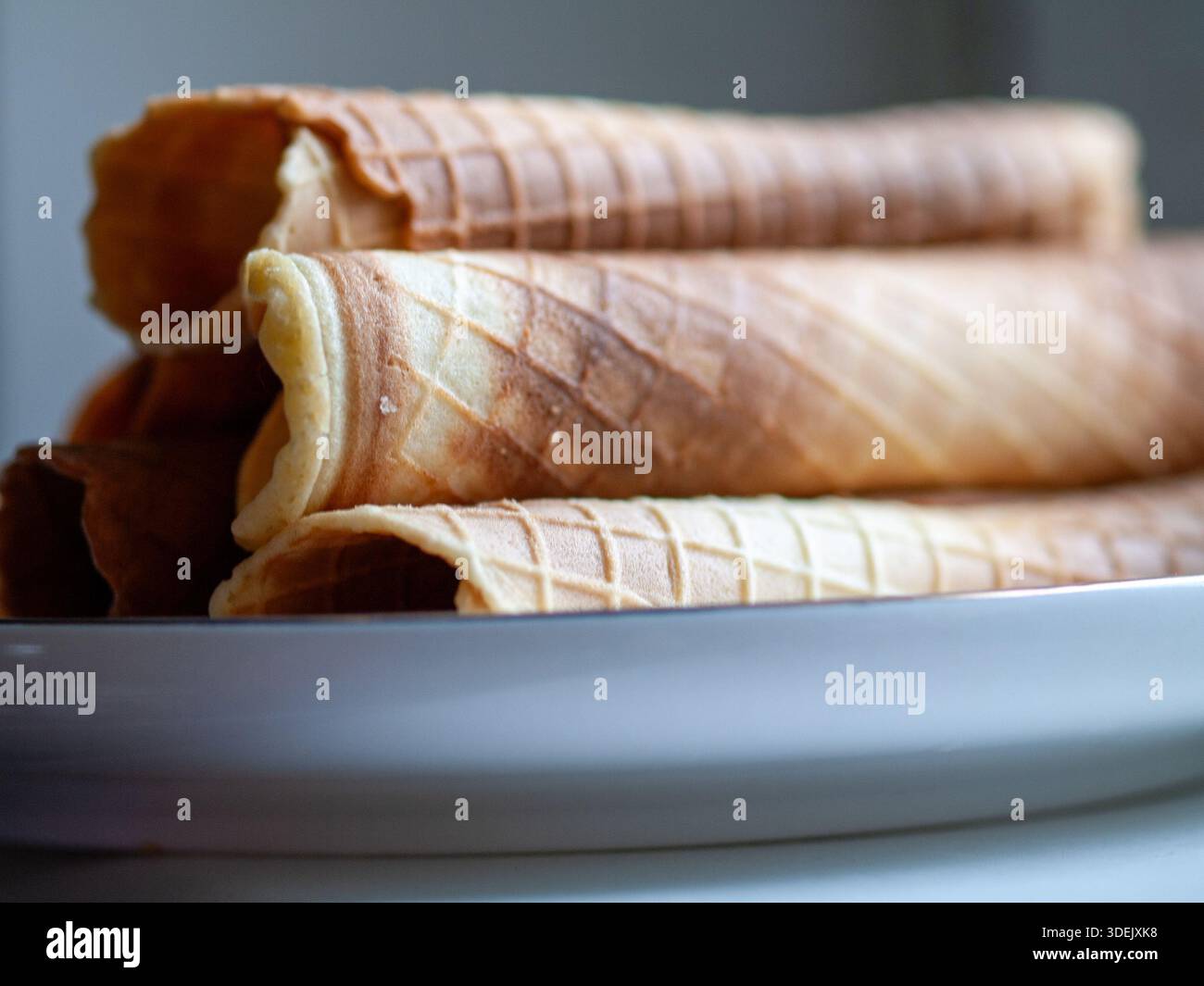 Coni di wafer arrotolati impilati in fila, vista ravvicinata dei coni di gelato vuoti. Foto Stock