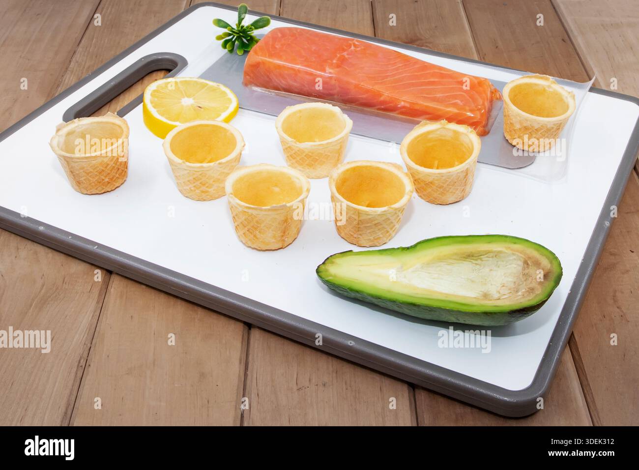 Filetto di salmone crudo con avocado limone e cialde su tagliere bianco Foto Stock