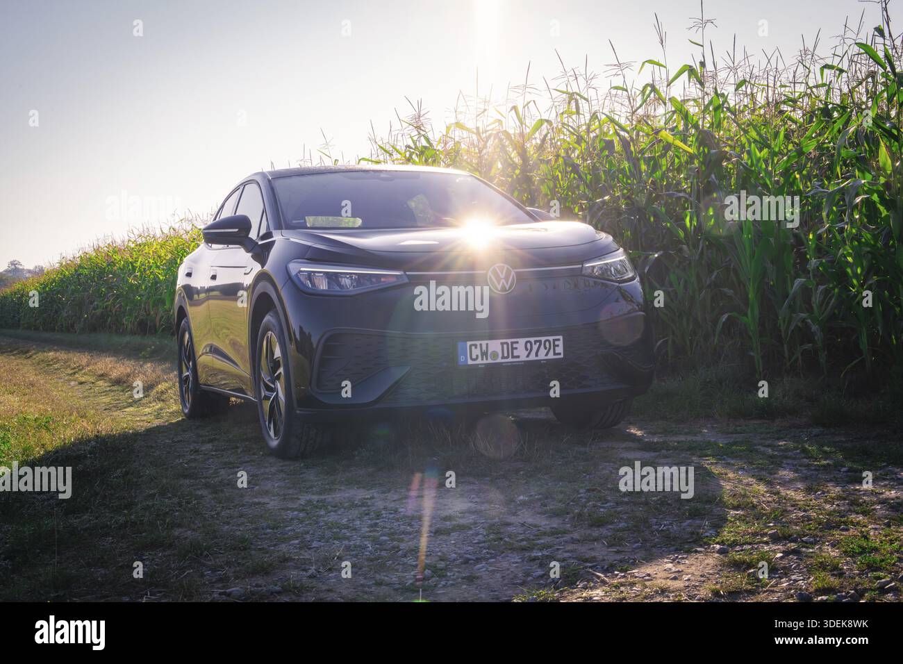 Auto nera su una strada sterrata accanto a un campo di mais con luce solare sul cofano, auto elettrica VW ID5, condivisione di e-car cervi, Calw, Germania Foto Stock