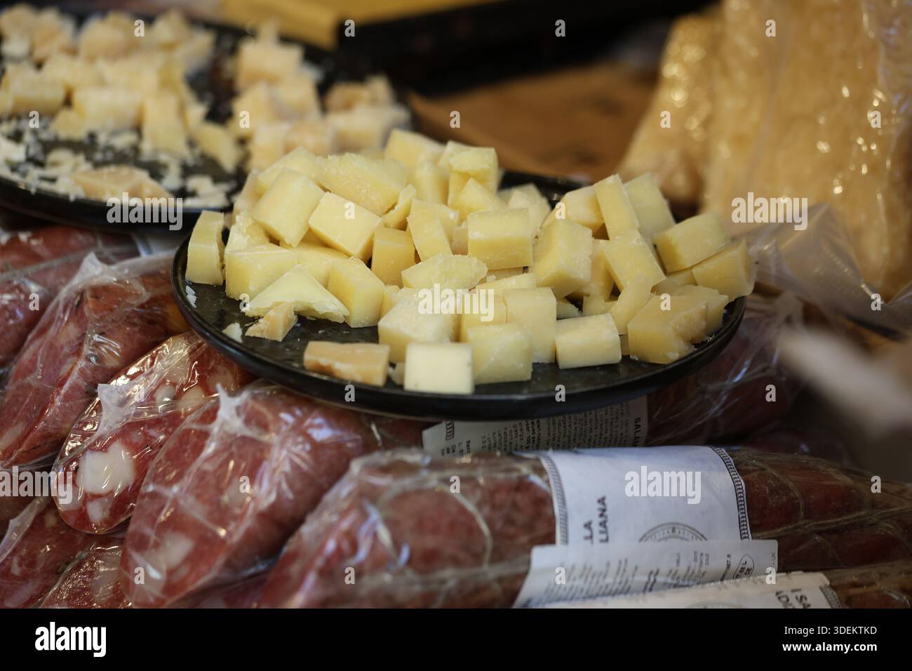 Vista ravvicinata del formaggio a dadini esposto per la degustazione in un mercato alimentare tradizionale con salumi Foto Stock