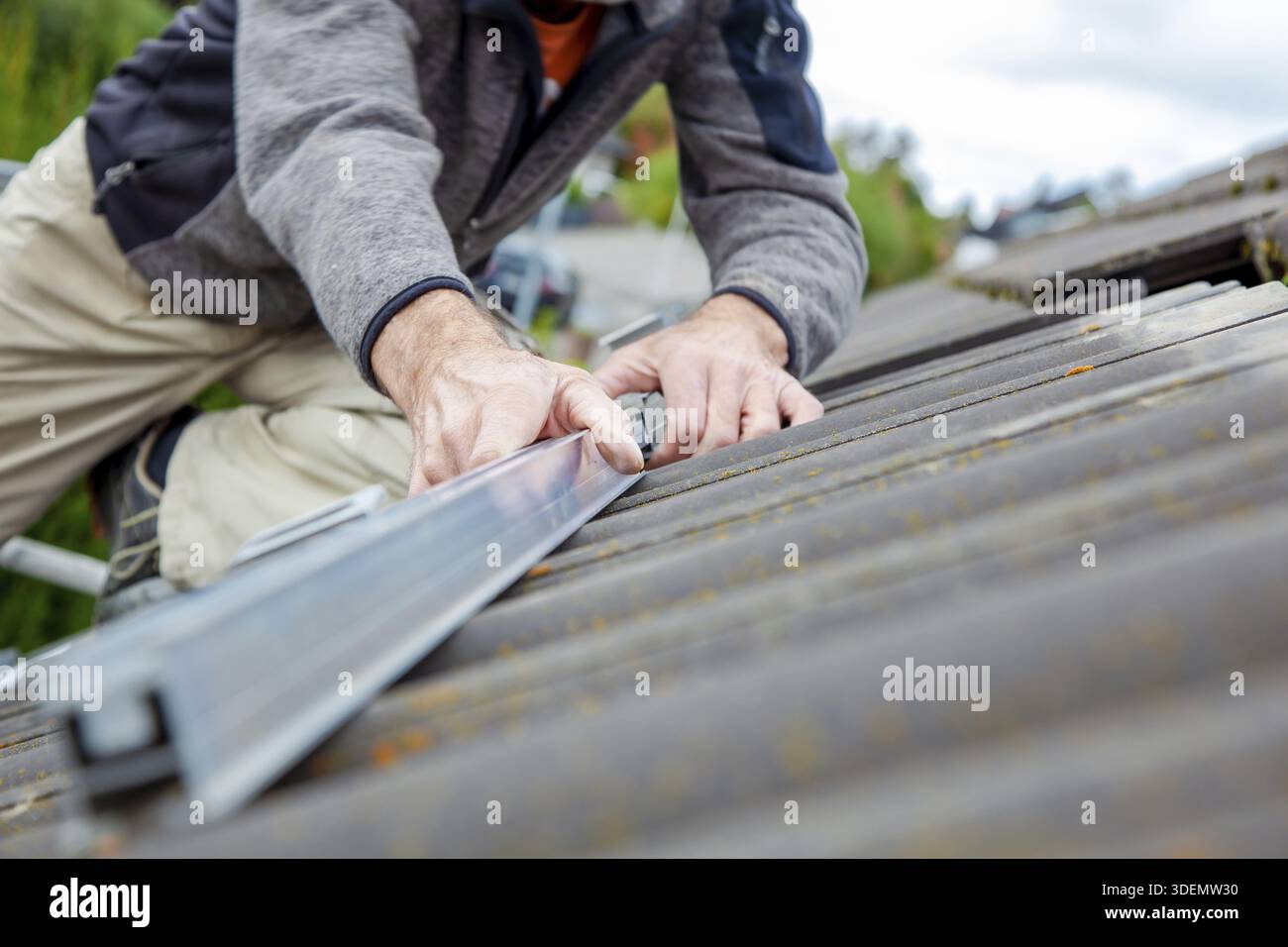 Roofer, operaio sul tetto. Lavori di copertura. Installazione cella solare. Preparazione dell'installazione di pannelli solari. fissaggio delle guide in cantiere Foto Stock