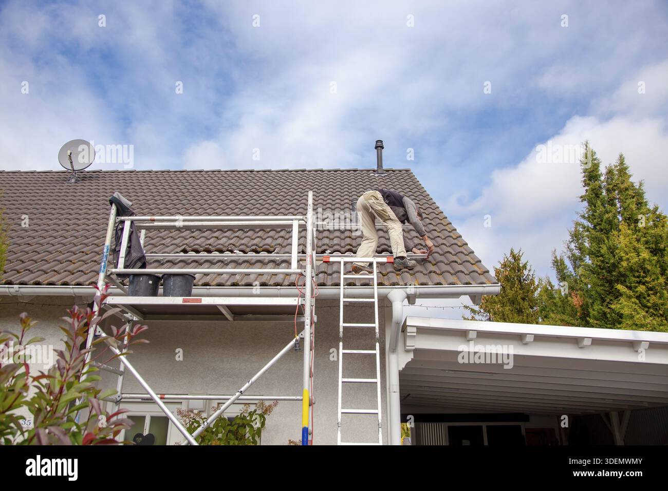 Roofer, operaio sul tetto. Lavori di copertura. Installazione cella solare. Preparazione dell'installazione di pannelli solari. fissaggio delle guide. impalcatura su vincolo Foto Stock