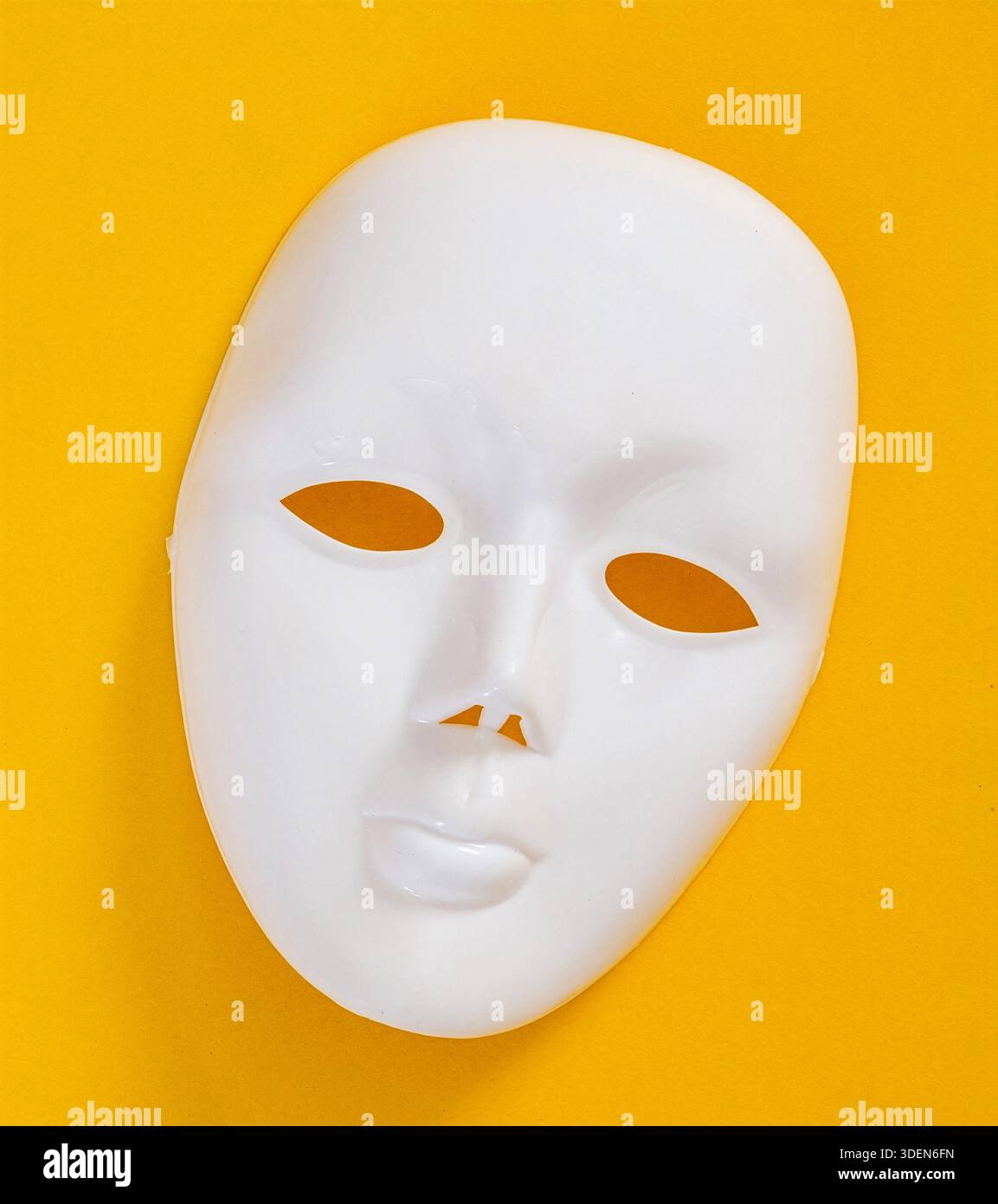 Maschera di plastica bianca che rappresenta un volto umano su uno sfondo giallo vibrante Foto Stock