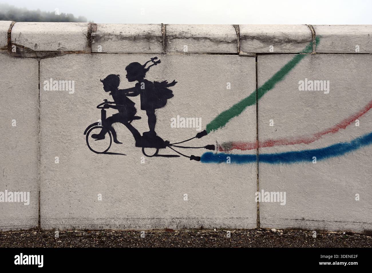 Anonimo stile Banksy Street Art o Stencil Graffiti con contorno stencil di due bambini o Boy and Girl in sella a una bicicletta su cemento Wall Francia Foto Stock