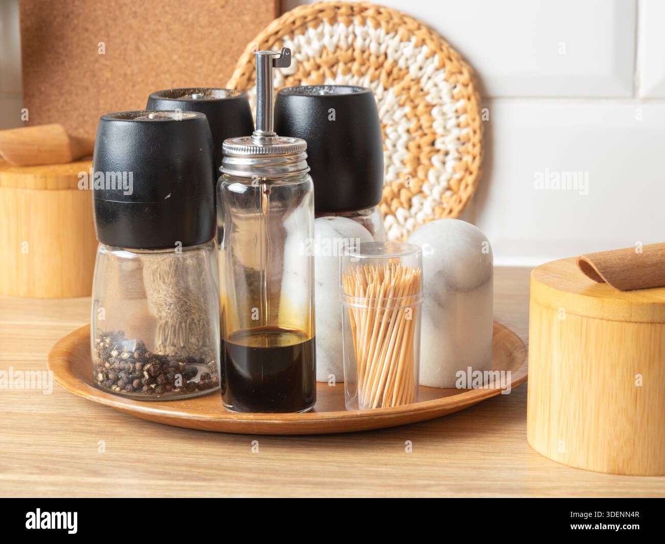 Un vassoio rotondo in bambù contiene una serie di macine di sale e pepe, una crosta di olio e aceto e un contenitore per stuzzicadenti, creando una linguetta ordinata ed elegante Foto Stock